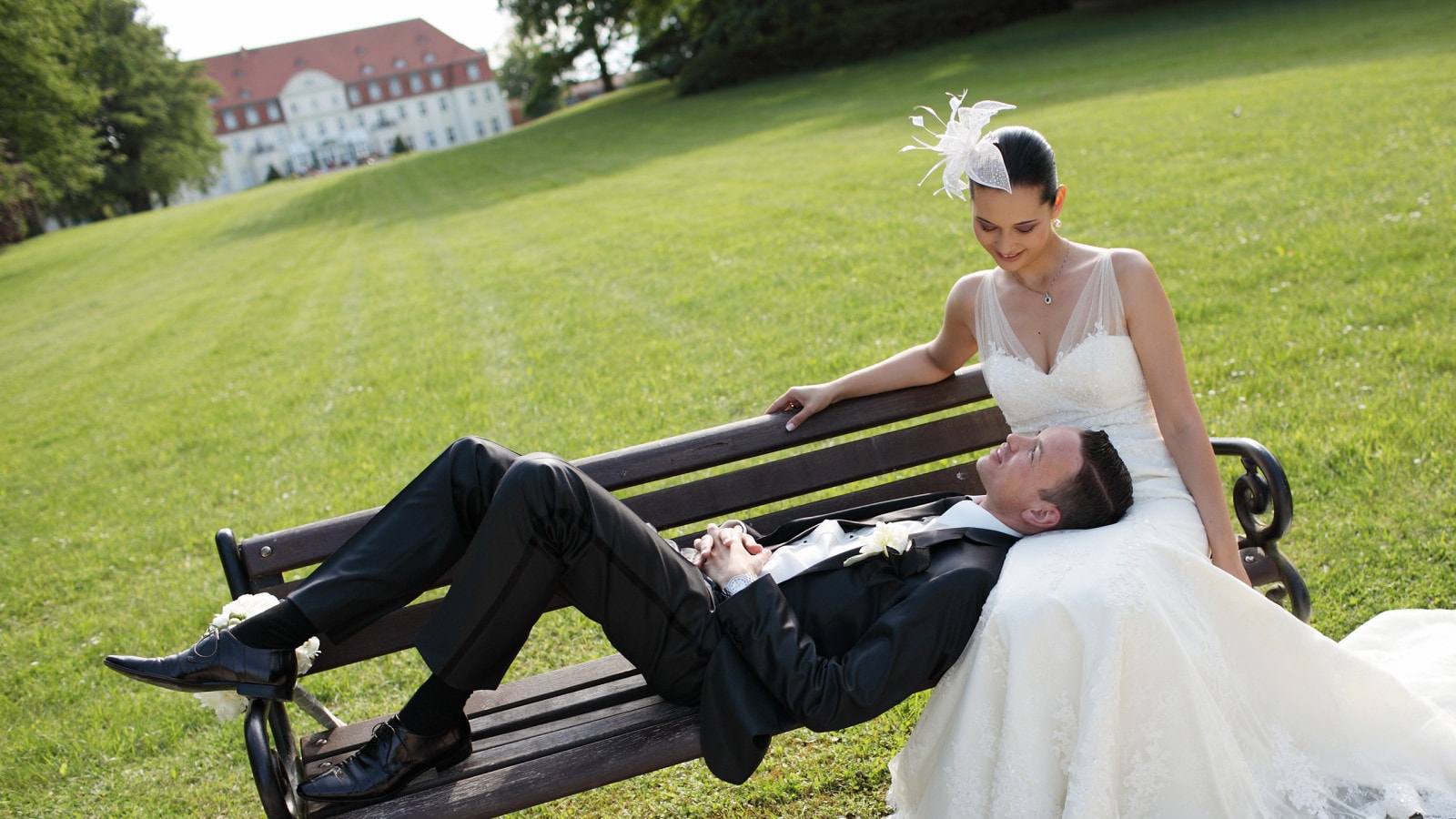 Ein Brautpaar sitzt auf einer Bank im Schlossgarten.