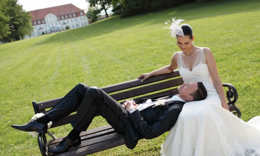 Ein Brautpaar auf einer Bank im Schlosspark.