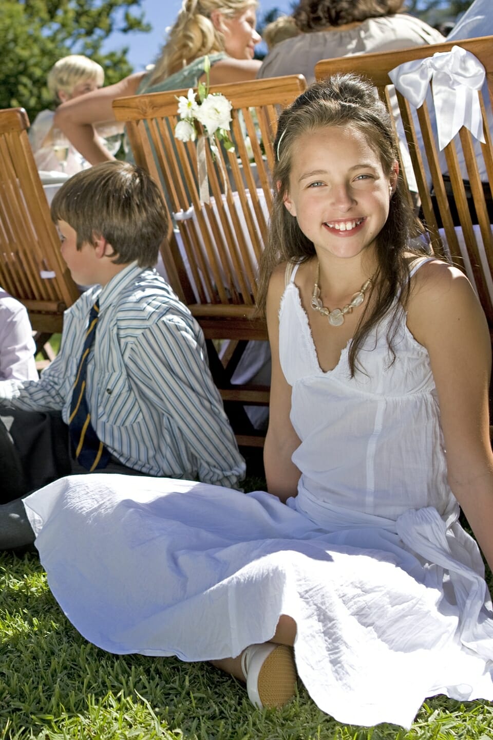 Kinder sitzen auf der Wiese bei einer Hochzeit.