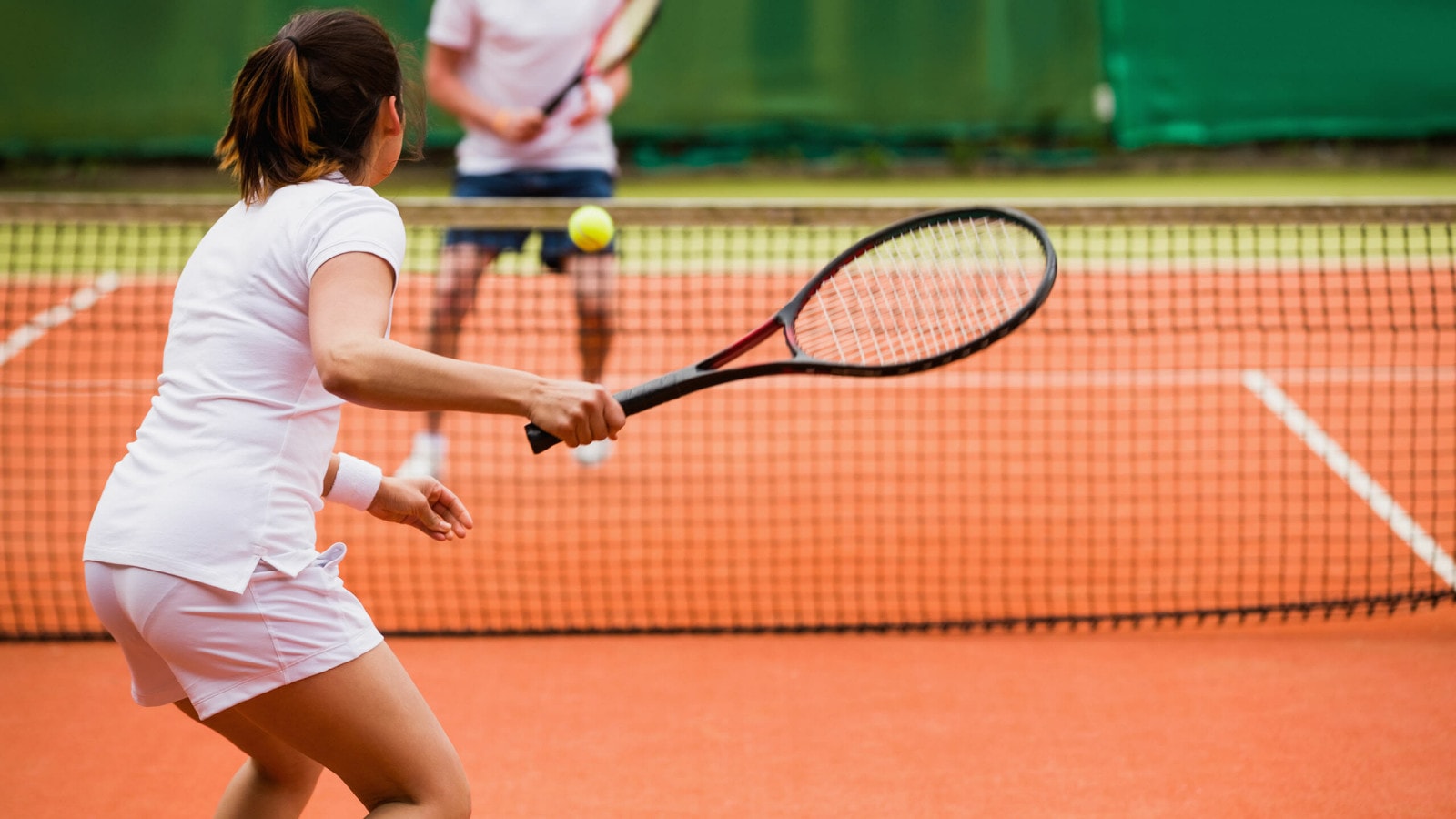 Eine Frau spielen gegen einen Mann Tennis.
