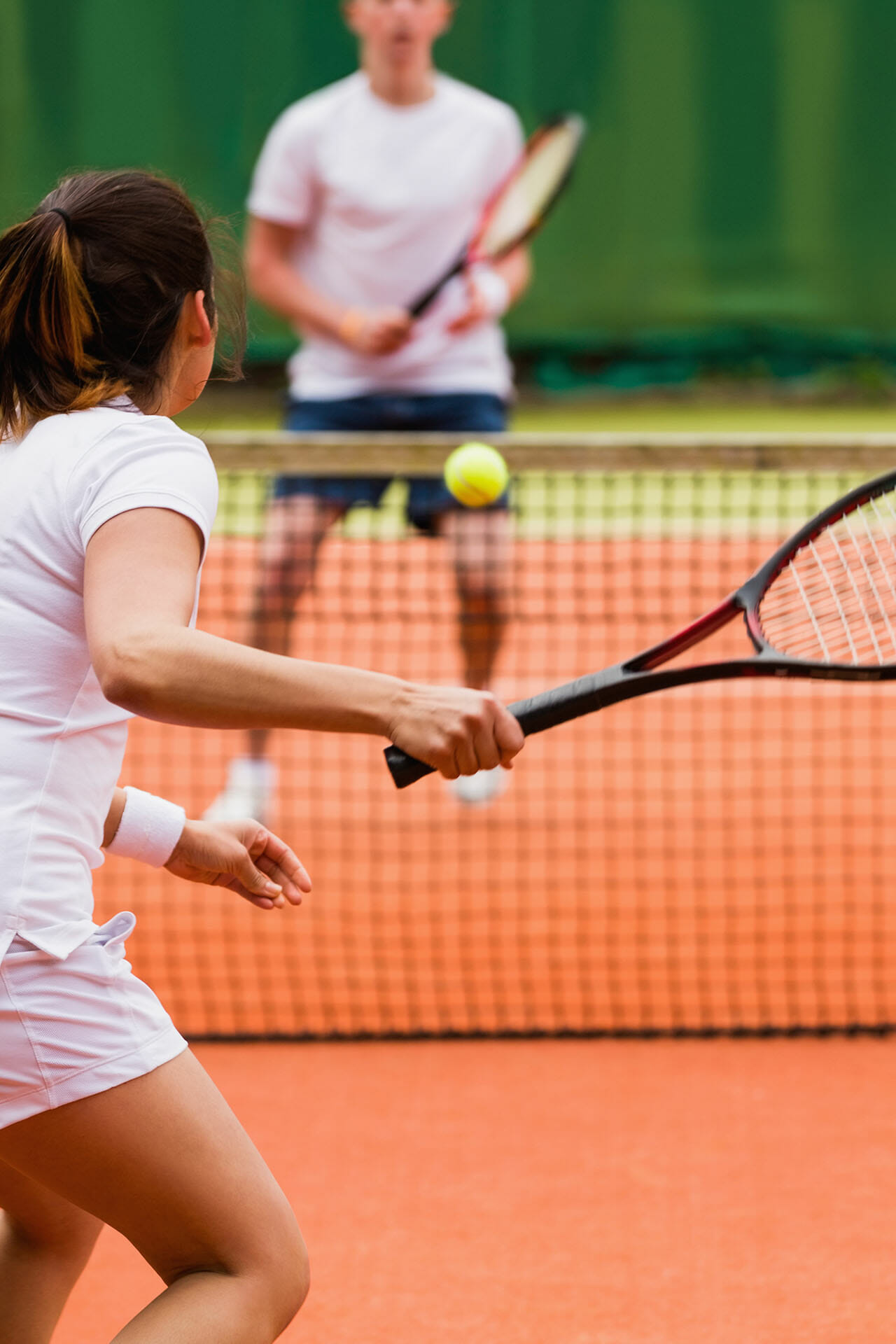 Eine Frau spielen gegen einen Mann Tennis.
