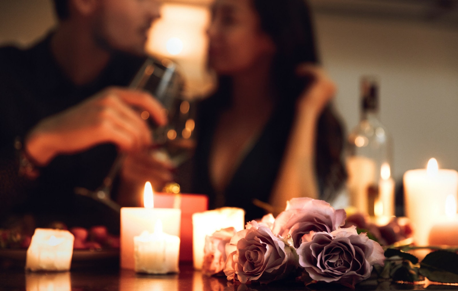 Ein Paar bei einem romantischen Dinner mit Kerzenschein und Rosen.
