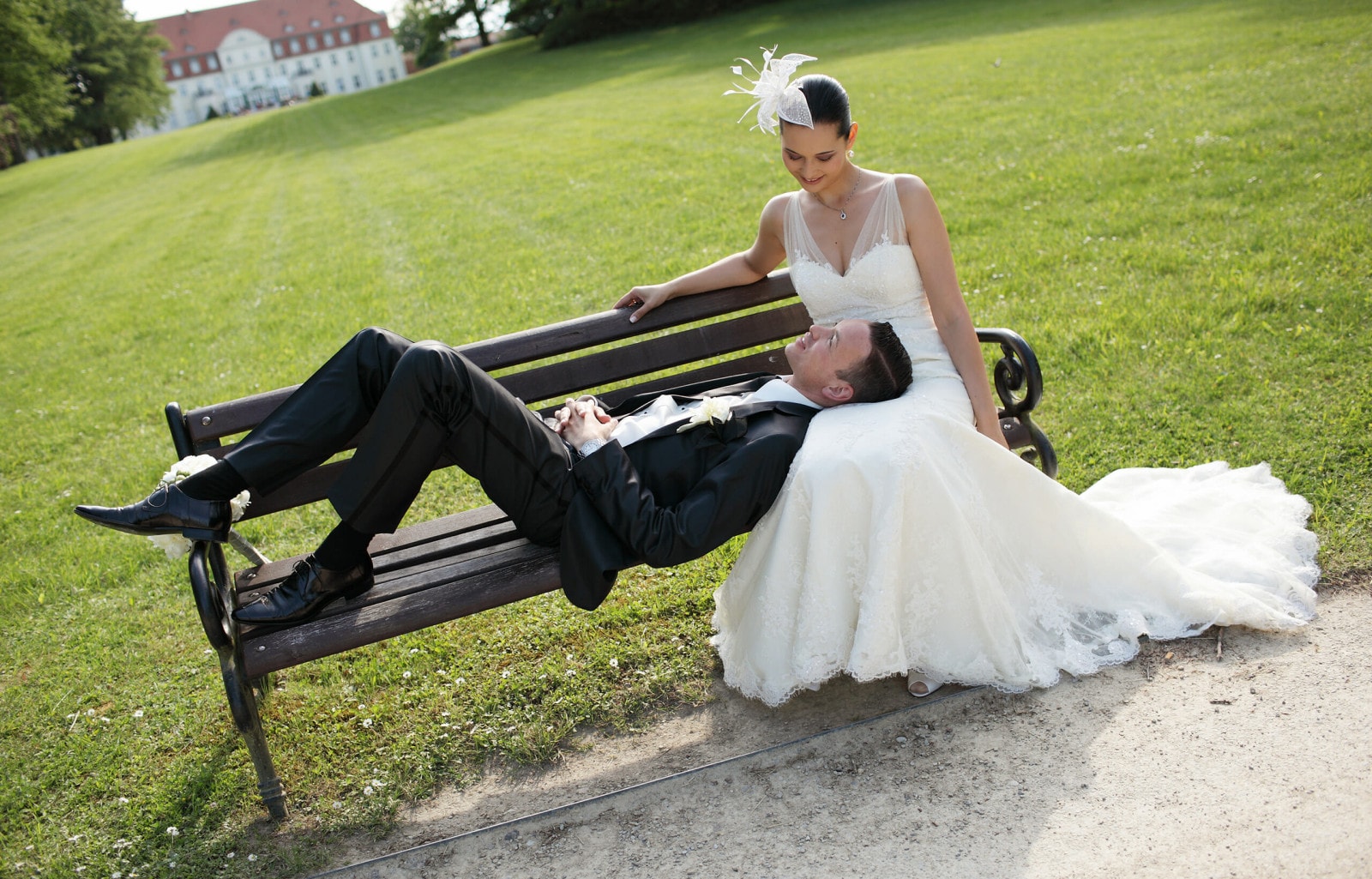 Ein Brautpaar sitzt auf einer Bank vor Schloss Fleesensee.