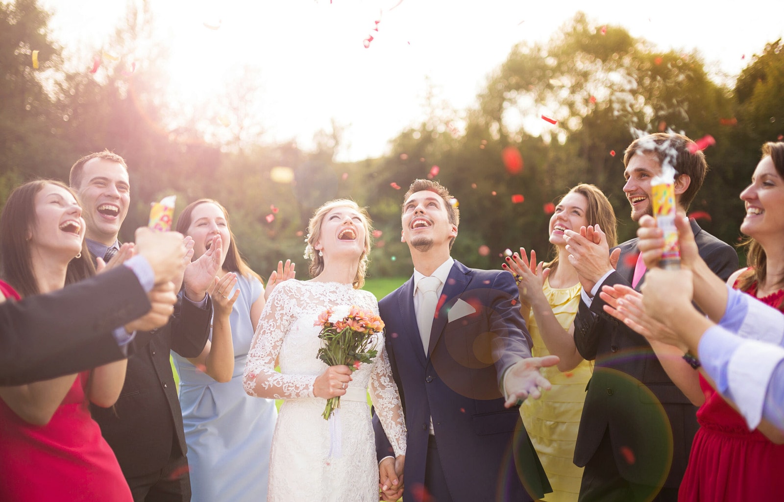 Eine Gruppe Menschen feiert mit einem Brautpaar.