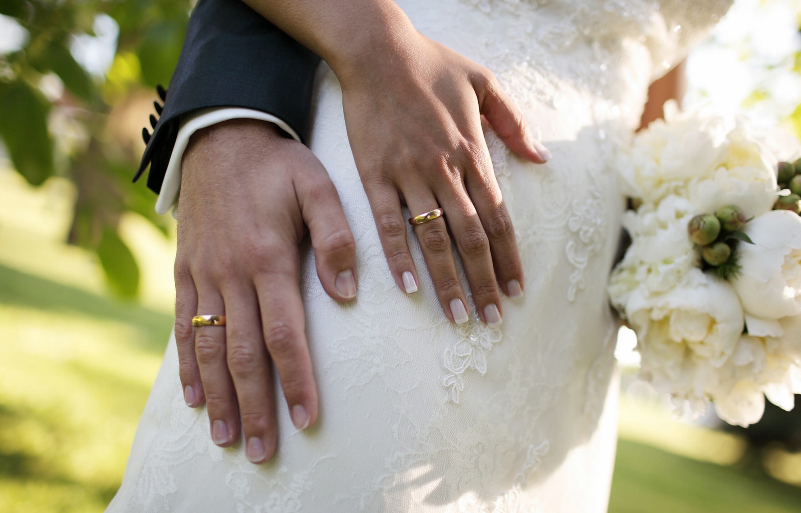 Die Hände eines Brautpaares mit Eheringen.