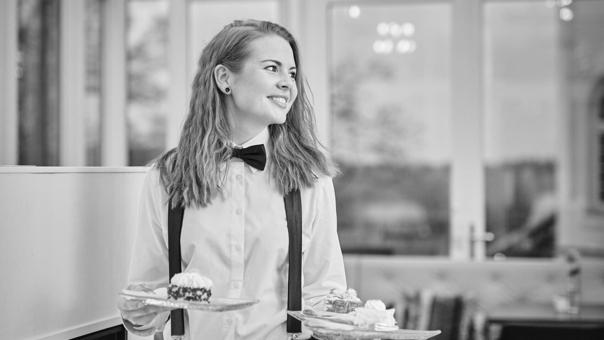 Eine Restaurantfachfrau trägt Teller.