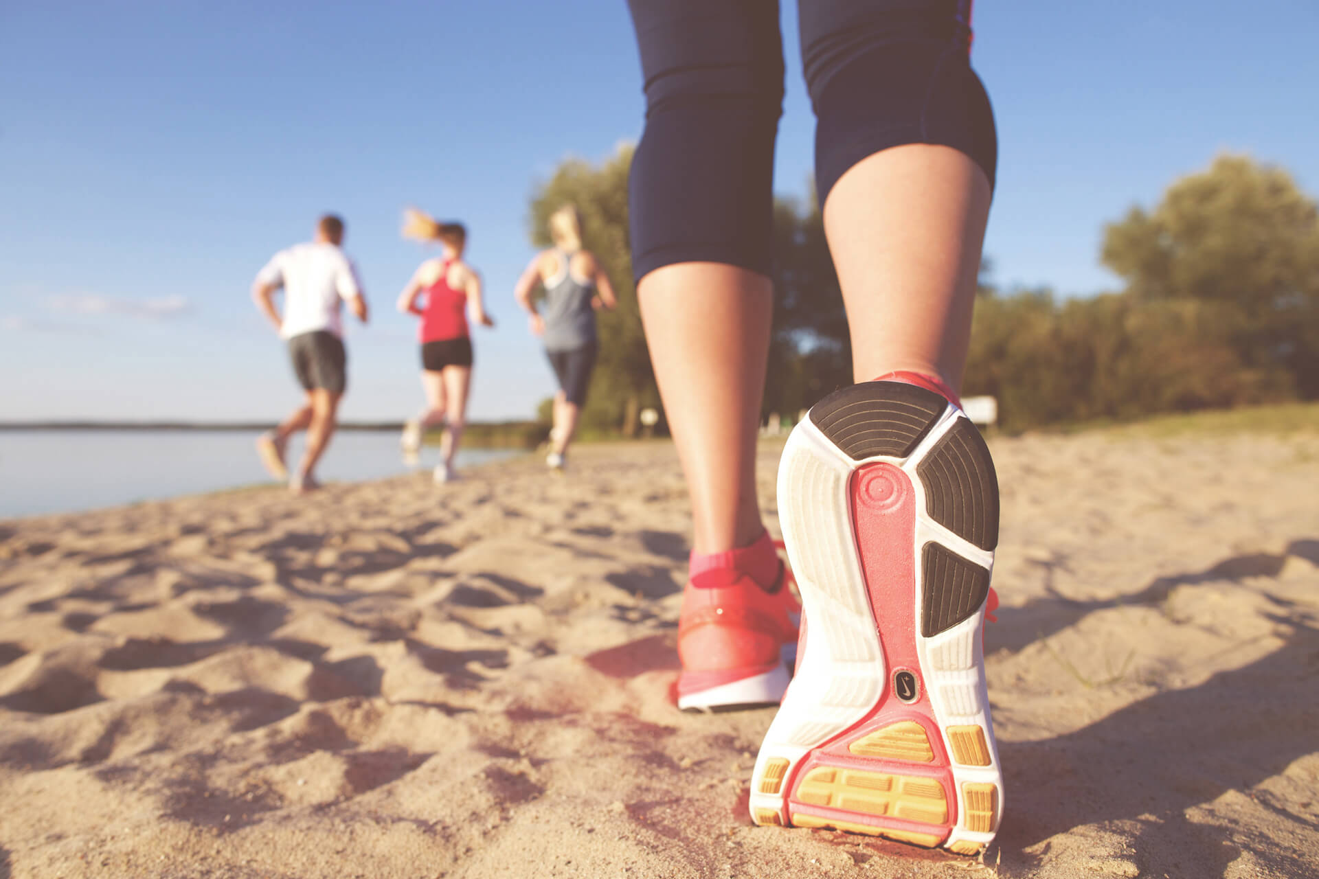 Die Schuhsohle eines Laufschuhs einer Joggerin am Strand.