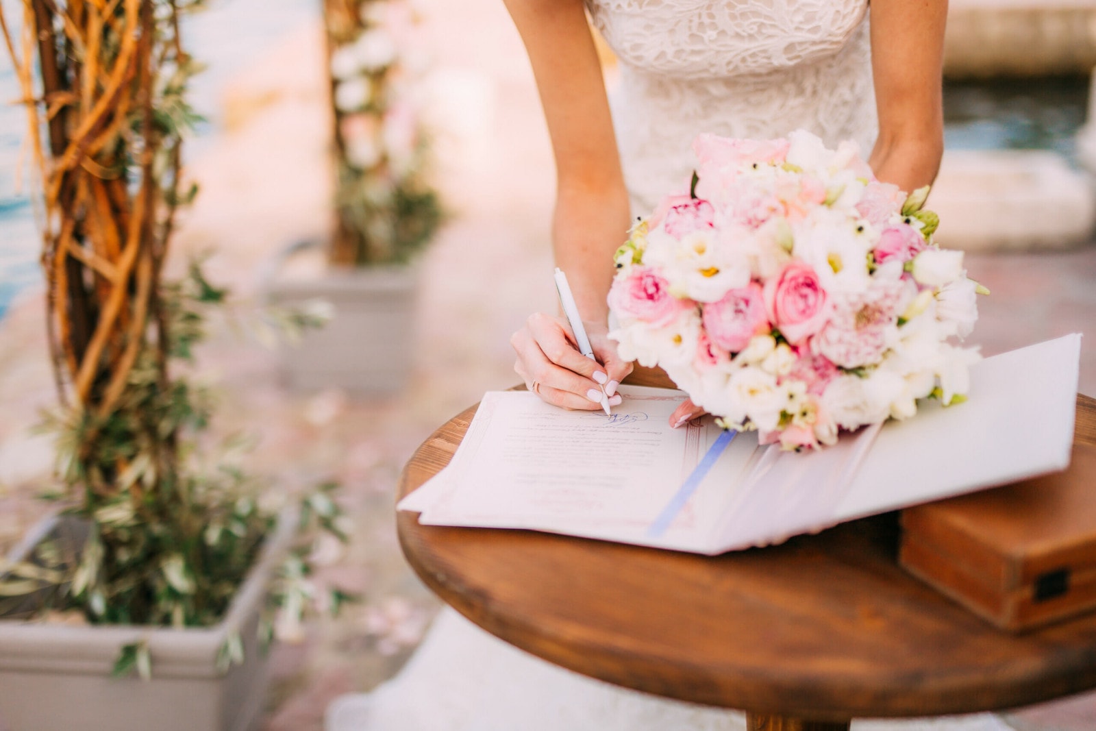 Eine Braut unterschreibt mit einem Blumenstrauß in der Hand.