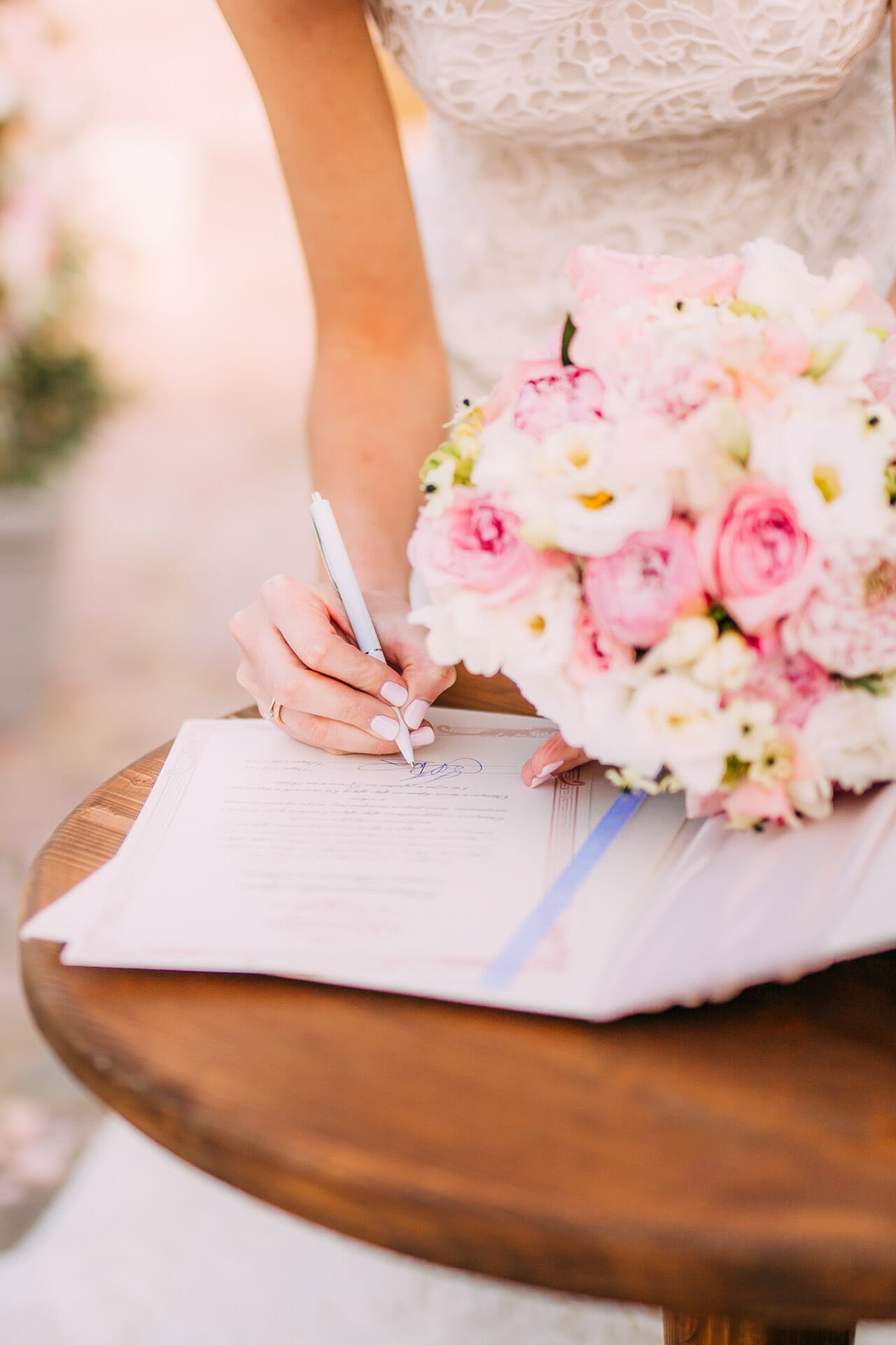 Eine Braut unterschreibt mit einem Blumenstrauß in der Hand.