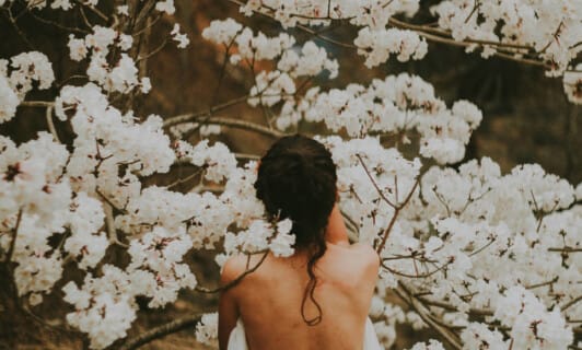 Frau mit Leinenhandschuh vom Schlosshotel Fleesensee steht im Kirschblütenbaum